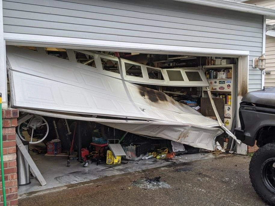 Damaged garage door, cluttered interior.