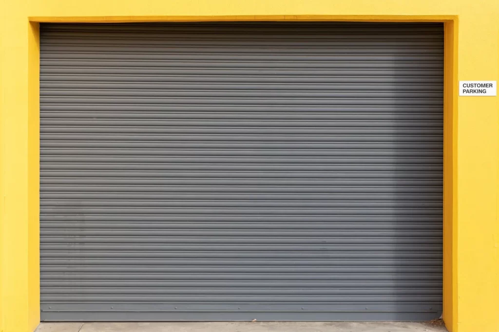 Rolling steel commercial garage door closed with yellow trim